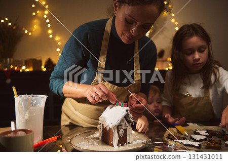 Mother And Two Children Decorate A Gingerbread House For Christmas At Cozy Home Mother And Two Children Decorate A Gingerbread House For Christmas At Cozy Home 131431011