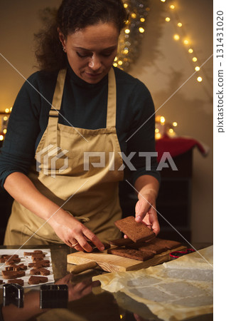 Caring Woman In Apron Slices Brownies For Christmas Cookies In Festive Kitchen 131431020