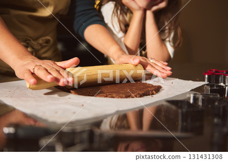 Family Baking Moment: Mother and Kids Rolling Chocolate Dough Together in Cozy Kitchen 131431308