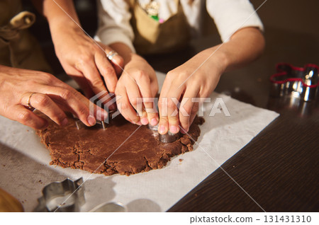 Family Baking Gingerbread Cookies Together: Hands Cutting Dough On Kitchen Table Family Baking Gingerbread Cookies Together: Hands Cutting Dough On Kitchen Table 131431310