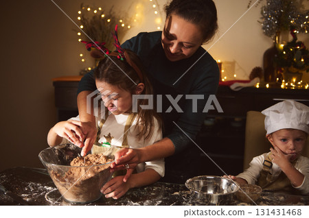 Joyful Mother Helps Daughter Bake Gingerbread With Son In Cozy Christmas Kitchen Joyful Mother Helps Daughter Bake Gingerbread With Son In Cozy Christmas Kitchen 131431468