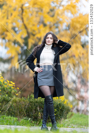 Young woman posing in autumn fashion with golden leaves 131432029