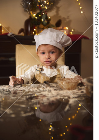 Little Chef Helps Bake Gingerbread as Christmas Lights Glow in Cozy Kitchen 131432077