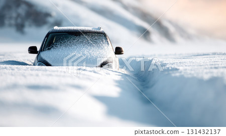 Vehicle is partially buried in deep snow, surrounded by a winter landscape, showcasing the challenges of driving in harsh weather conditions 131432137