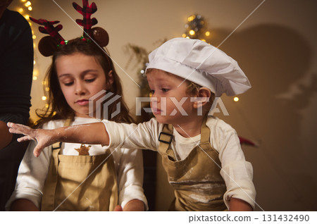 Young Chef and Sister Decorate Gingerbread House During Cozy Christmas at Home 131432490