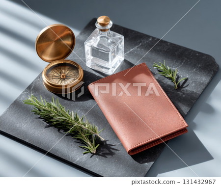 Flat-lay composition of minimalist orange leather wallet with compass and rosemary on gray background under sunlight 131432967