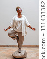 Joyful plus-size Black woman practicing yoga indoors standing on stone in tree pose 131433382
