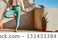 Close-up of woman practicing standing yoga pose outdoors in sunlight, focusing on balance, harmony, and physical awareness. 131433384
