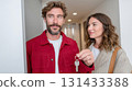 Couple entering new apartment and holding keys with excitement in bright hallway 131433388