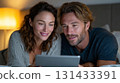 Couple relaxing in bed with tablet enjoying digital content in warm and cozy evening lighting 131433391