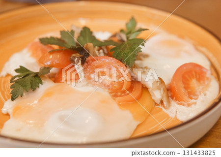 Fried eggs with tomato, mushroom, and parsley served on a plate for a healthy breakfast. Natural and fresh food concept. Fried eggs with tomato, mushroom, and parsley served on a plate for a healthy breakfast. Natural and fresh food concept. 131433825