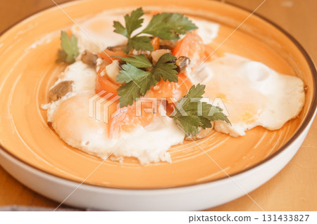 Fried eggs with tomato, mushroom, and parsley served on a plate for a healthy breakfast. Natural and fresh food concept. Fried eggs with tomato, mushroom, and parsley served on a plate for a healthy breakfast. Natural and fresh food concept. 131433827