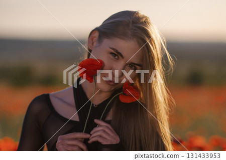 Poppies Model Portrait Sunset: Woman with flowers poses in poppy field during warm sunset light. Poppies Model Portrait Sunset: Woman with flowers poses in poppy field during warm sunset light. 131433953