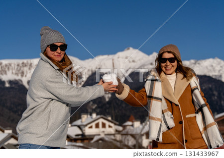 Snowball Fight, Mountains, Winter: Two women playfully exchange snowballs in a snowy mountain village during winter. Snowball Fight, Mountains, Winter: Two women playfully exchange snowballs in a snowy mountain village during winter. 131433967