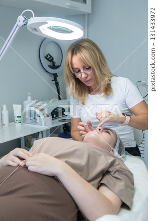Cosmetology Facial Treatment Clinic Skincare: Professional performs facial treatment on client in modern clinic. 131433972