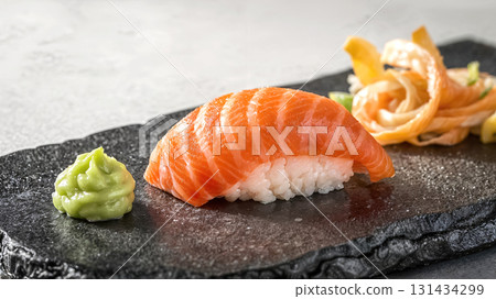 Fresh salmon sushi nigiri with rice, wasabi and pickled ginger on black stone plate. Japanese traditional cuisine. Gourmet seafood dish. Authentic Asian food served in elegant restaurant setting. Fresh salmon sushi nigiri with rice, wasabi and pickled ginger on black stone plate. Japanese traditional cuisine. Gourmet seafood dish. Authentic Asian food served in elegant restaurant setting. 131434299