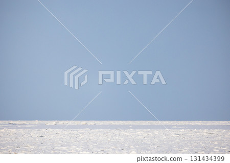 A vast, snow-covered frozen sea stretches to a distant horizon 131434399