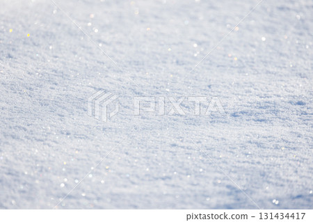 A sunlit, snow-covered ground glistens with tiny crystals, background photo texture 131434417