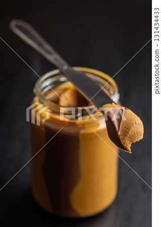 Two-tone nut chocolate spread in jar on black table. 131434433