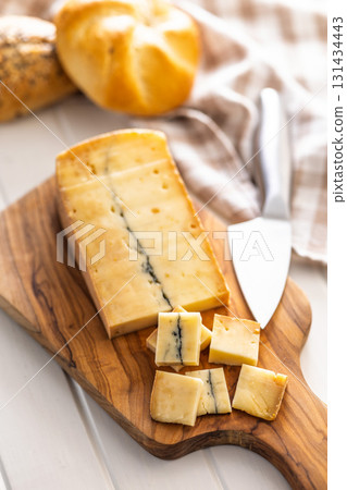 Morbier cheese. Delicious french cheese with mold on cutting board on white table. Morbier cheese. Delicious french cheese with mold on cutting board on white table. 131434443