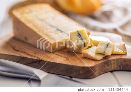 Morbier cheese. Delicious french cheese with mold on cutting board on white table. Morbier cheese. Delicious french cheese with mold on cutting board on white table. 131434444