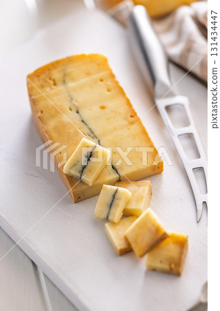 Morbier cheese. Delicious french cheese with mold on cutting board on white table. Morbier cheese. Delicious french cheese with mold on cutting board on white table. 131434447
