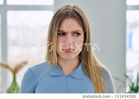 Headshot portrait of young serious sad woman looking at camera 131434508