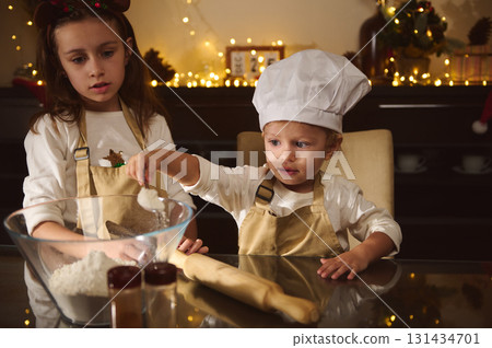 Two Kids Baking Gingerbread With Chef Hat In Cozy Christmas Kitchen 131434701