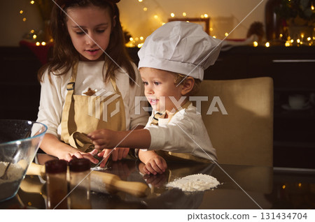 Young Brother And Sister Bake Gingerbread With Chef Hat In Cozy Christmas Kitchen Young Brother And Sister Bake Gingerbread With Chef Hat In Cozy Christmas Kitchen 131434704