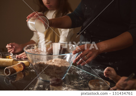 Family Baking Together: Pouring Sugar and Mixing Dough in a Cozy Kitchen Scene 131434761
