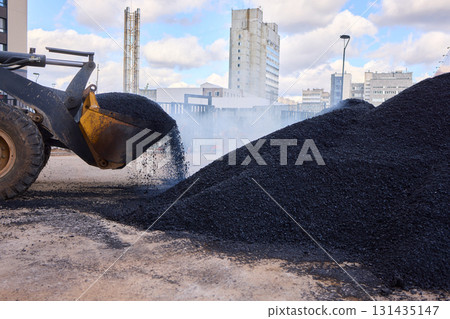 Heavy Machinery Loading Black Aggregate Material at the Construction Site for Development Heavy Machinery Loading Black Aggregate Material at the Construction Site for Development 131435147