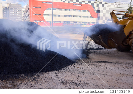 Heavy Machinery Loading Black Aggregate Material at the Construction Site for Development Heavy Machinery Loading Black Aggregate Material at the Construction Site for Development 131435149