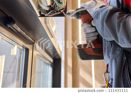 An Electrician Skillfully Installing Electrical Components Using a Power Drill Tool An Electrician Skillfully Installing Electrical Components Using a Power Drill Tool 131435151