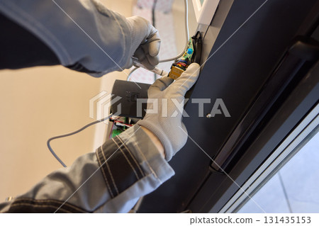 A technician is repairing an advanced automated door system with electrical tools 131435153
