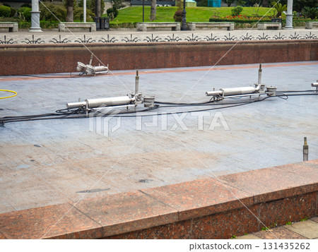 Empty fountain in a city park. Dehumidification. Cleaning the fountain with a hose. The device of the fountain. Pipes for water supply. Water hoses. Modern technologies 131435262