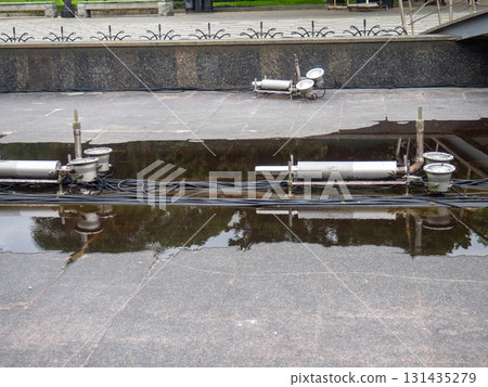 Empty fountain in a city park. Dehumidification. Cleaning the fountain with a hose. The device of the fountain. Pipes for water supply. Water hoses. Modern technologies 131435279