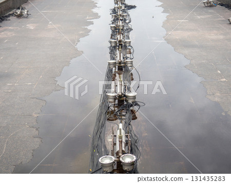 Empty fountain in a city park. Dehumidification. Cleaning the fountain with a hose. The device of the fountain. Pipes for water supply. Water hoses. Modern technologies. 131435283