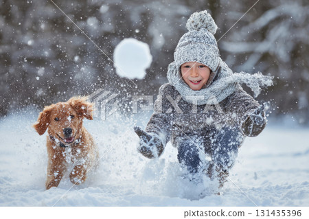Smiling boy in warm clothes playing with dog in snow, throwing snowball in winter forest 131435396