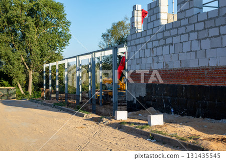 Building under construction at construction site with telescopic crane and loader in the background. Building under construction at construction site with telescopic crane and loader in the background. 131435545