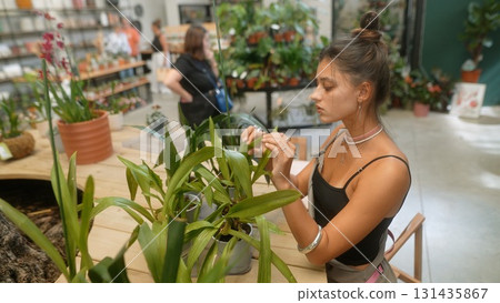 A Young Woman is Actively Caring for Beautiful Plants Inside a Modern Botanical Store 131435867