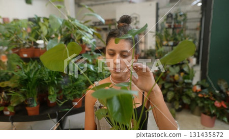 A woman engaging meaningfully with a diverse range of exotic plants in a stunning botanical setting 131435872