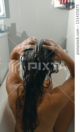 A woman washes her hair in a modern bathroom, enjoying a refreshing and relaxing experience A woman washes her hair in a modern bathroom, enjoying a refreshing and relaxing experience 131435875