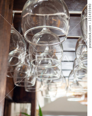 Glasses hang over the bar counter. The glasses are turned upside down. restaurant interior. Concept of drinking alcoholic beverages. Glass glasses for wine. 131435940