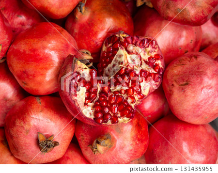 Fresh pomegranate harvest. Background of winter fruits. Red fruits. Opened pomegranate fruit. Pulp. Fresh pomegranate harvest. Background of winter fruits. Red fruits. Opened pomegranate fruit. Pulp. 131435955