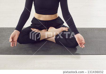 Yogi woman close up wearing black sportswear sitting in Padmasana pose lotus position, finger mudra  131436032