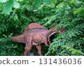 An Ankylosaurus dinosaur statue stands among the forests natural landscape, surrounded by terrestrial plants and groundcover 131436036