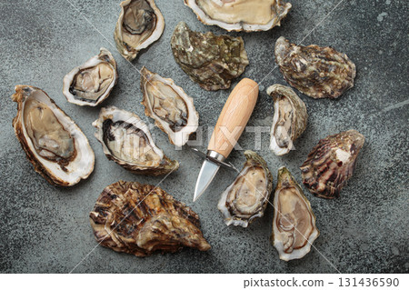 Fresh open and closed oysters with oyster knife on gray background top view 131436590