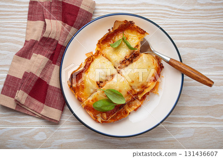 Italian lasagna with cheese and basil on plate on white rustic wooden background top view 131436607