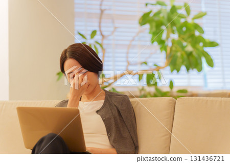 A woman with eyestrain working on a computer at night A woman with eyestrain working on a computer at night 131436721