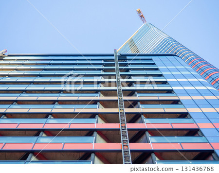A newly built house. Glazed skyscraper. Reflection of the sky in the windows. Multi-apartment modern housing. A newly built house. Glazed skyscraper. Reflection of the sky in the windows. Multi-apartment modern housing. 131436768